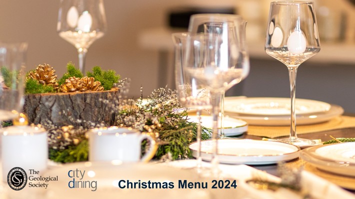 wine galsses, plates and festive pine cone decor on a table